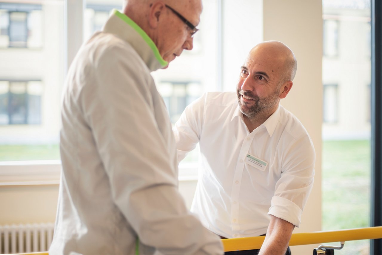 Patient beim Gehtraining mit dem Arzt nach der Gelenk-OP