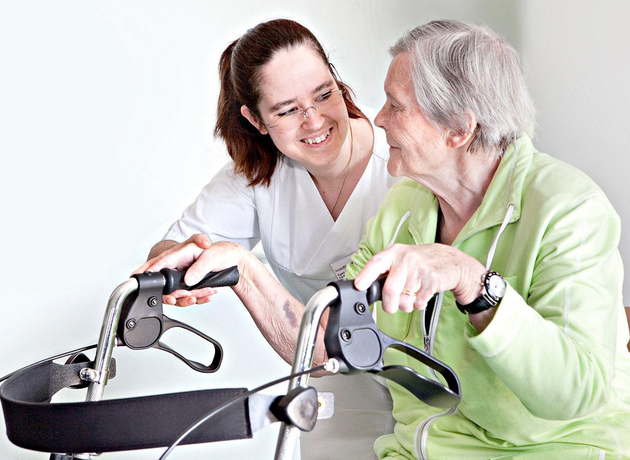 Pflegerin hilft geriatrischer Patientin