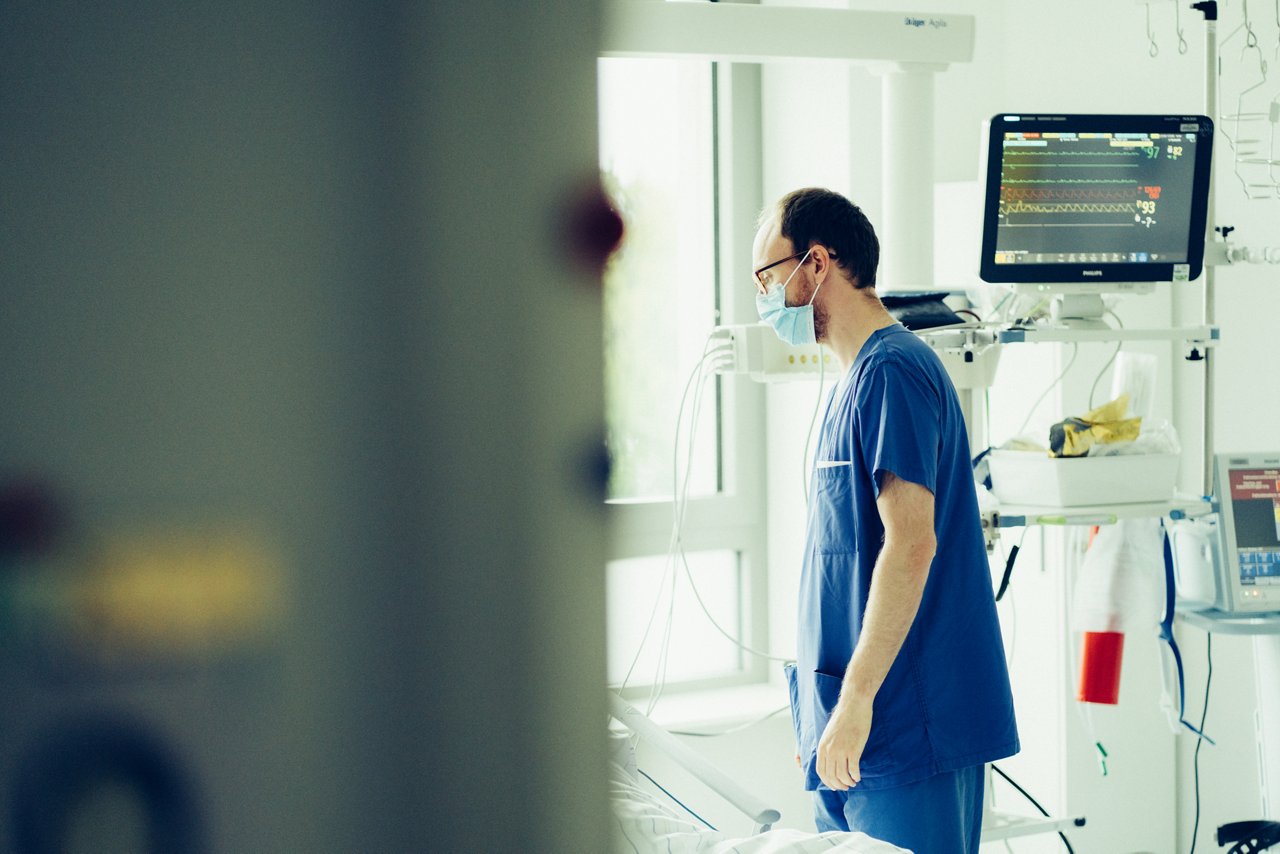 Pfleger oder Arzt steht am Krankenbett und spricht mit Patient:in