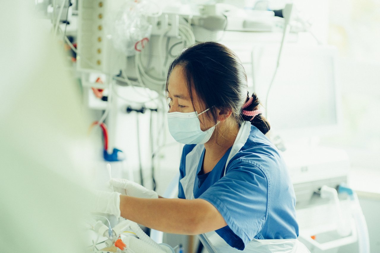 Eine Intensivpflegekraft kümmert sich um einen/eine Patienten/Patientin