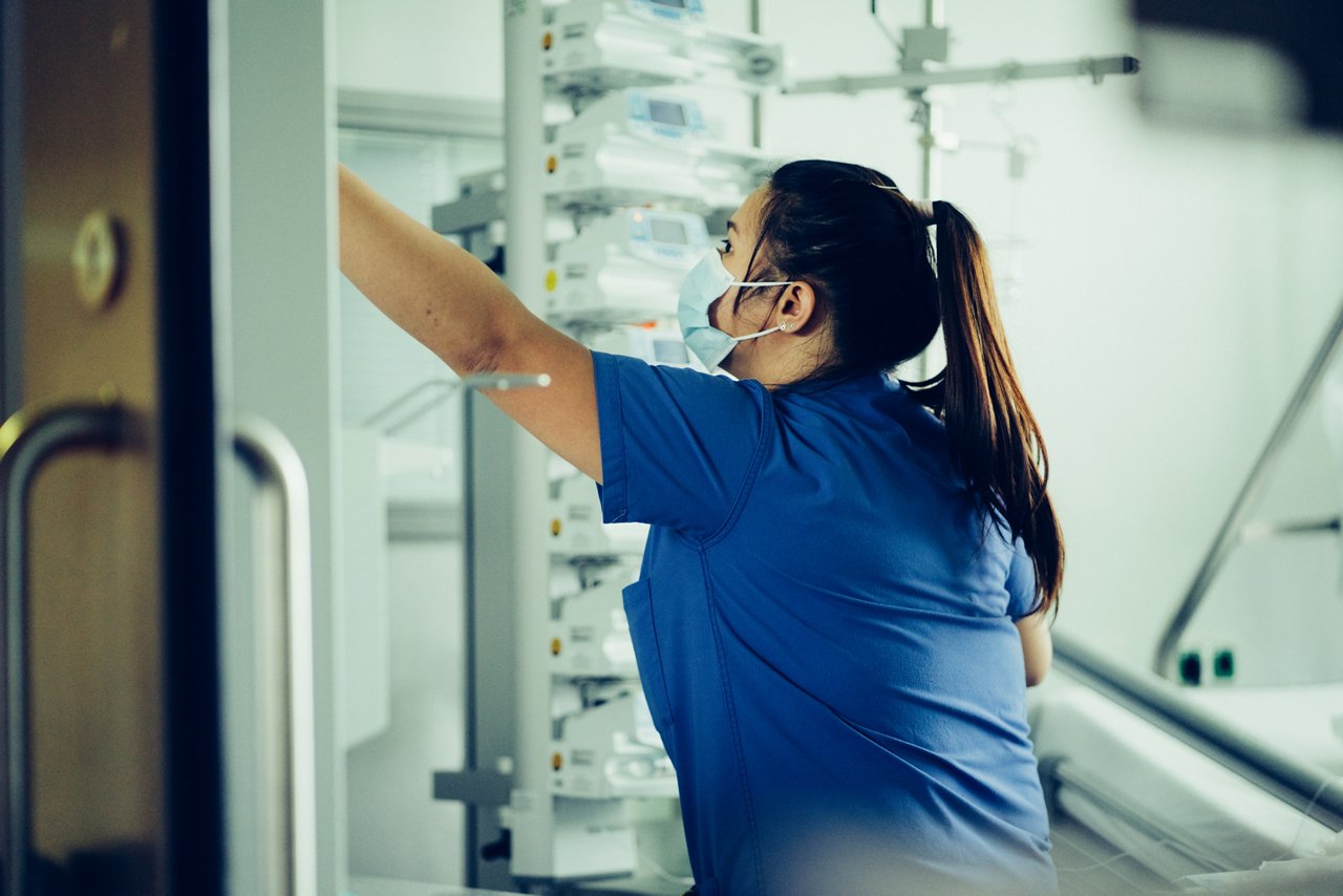 Intensivpflegekraft scheint nach etwas zu greifen, was nicht im Bild ist