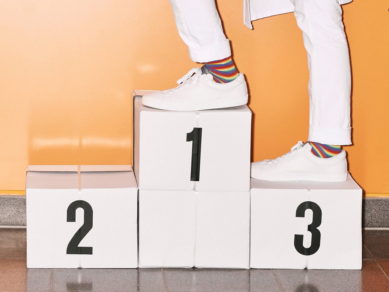 Arzt besteigt Siegertreppchen mit bunten Helios Socken und Sneakern #EchtesLeben 2022/23