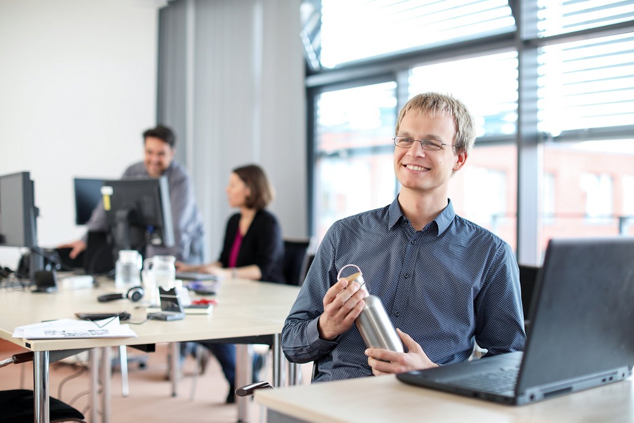 IT Mitarbeiter mit Trinkflasche am Schreibtisch