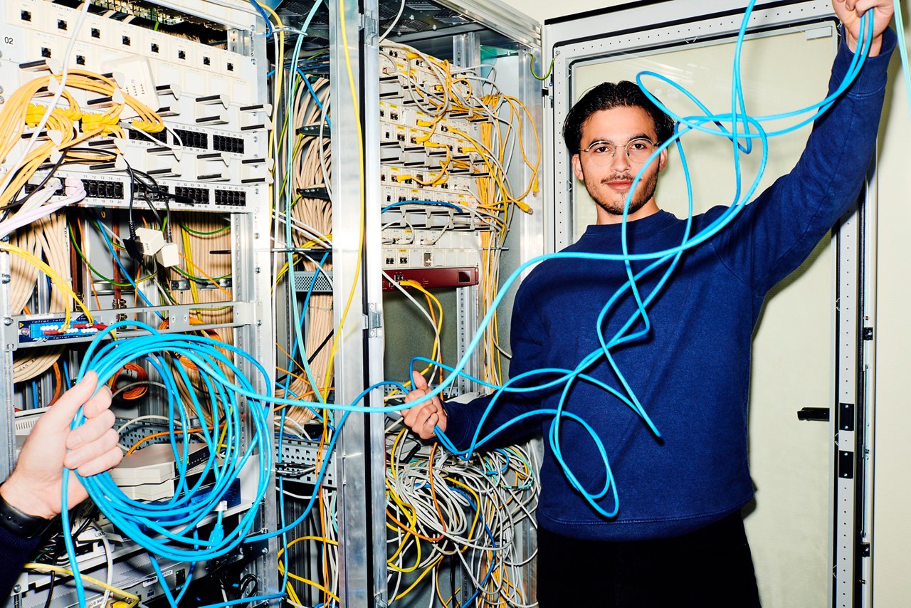  Mitarbeiter mit Kabel in der Hand neben Serverschrank