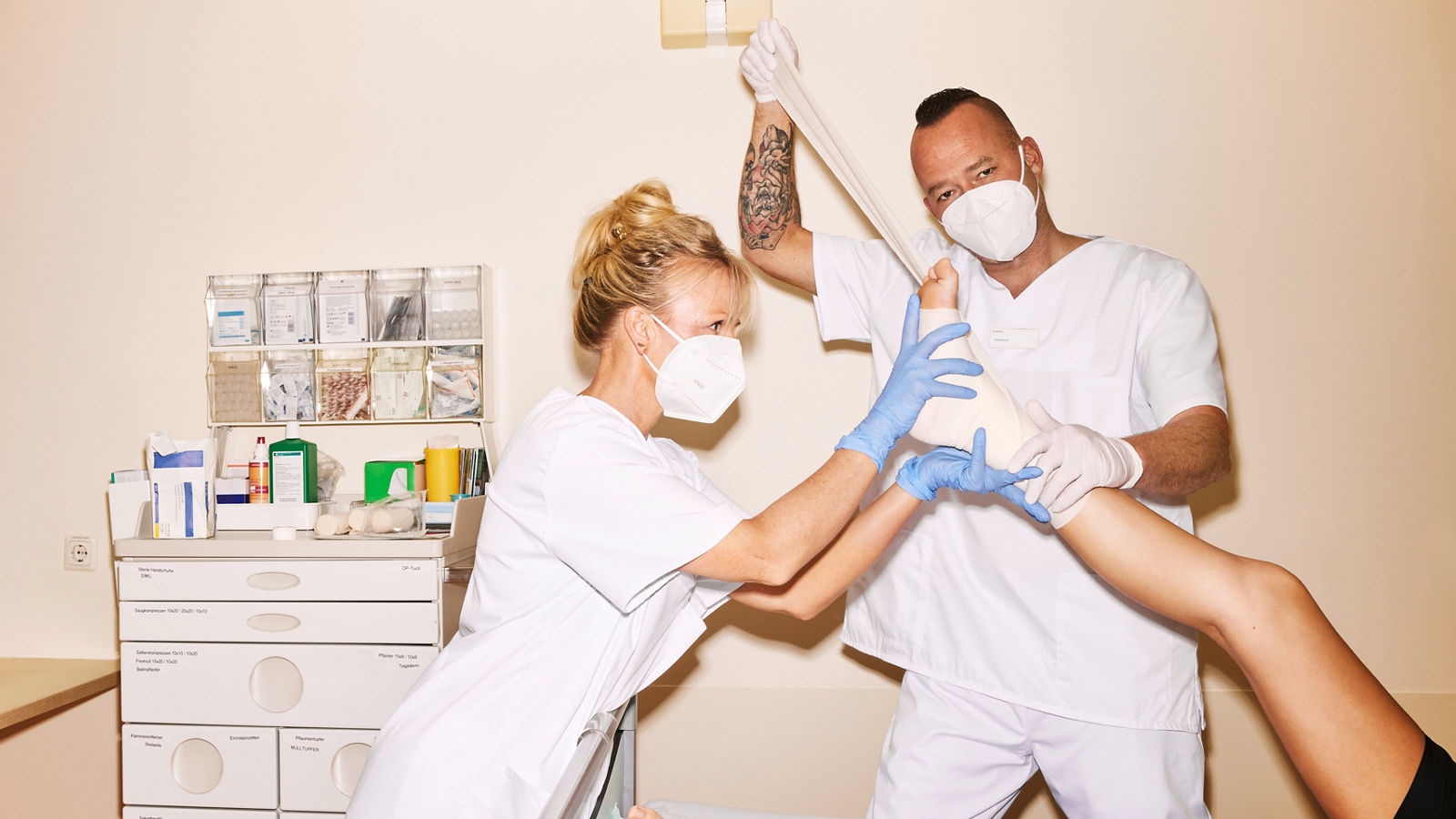 Pflegefach-Team bandagiert den hoch gelegten Fuß eines Patienten #EchtesLeben 2022/23