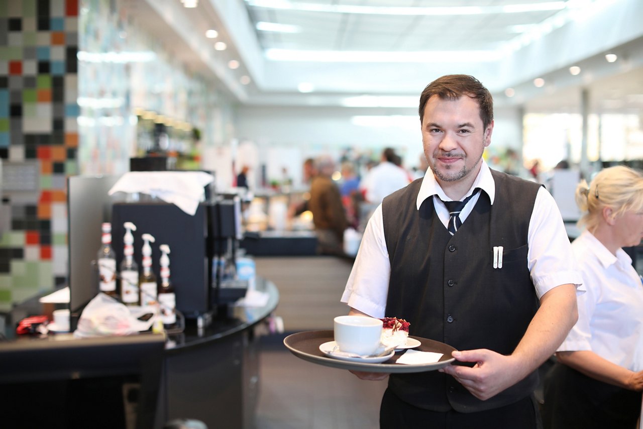 Servicekraft hält in der Cafeteria ein Tablett