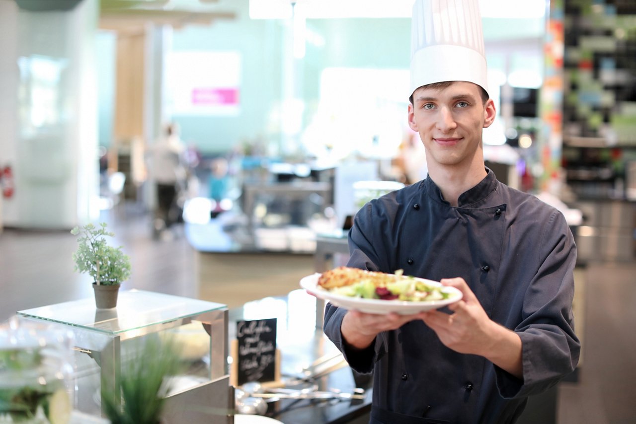 Koch hält ein Teller mit Essen in den Händen