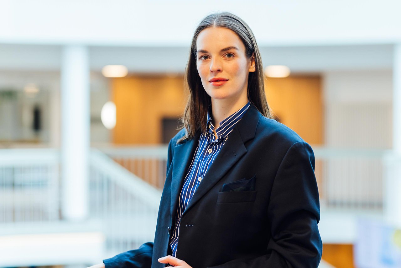 Professionelle Frau in einem eleganten Anzug, die selbstbewusst in einem modernen Büro steht. Ihr Stil kombiniert formelle Eleganz mit einem Hauch von Kreativität.