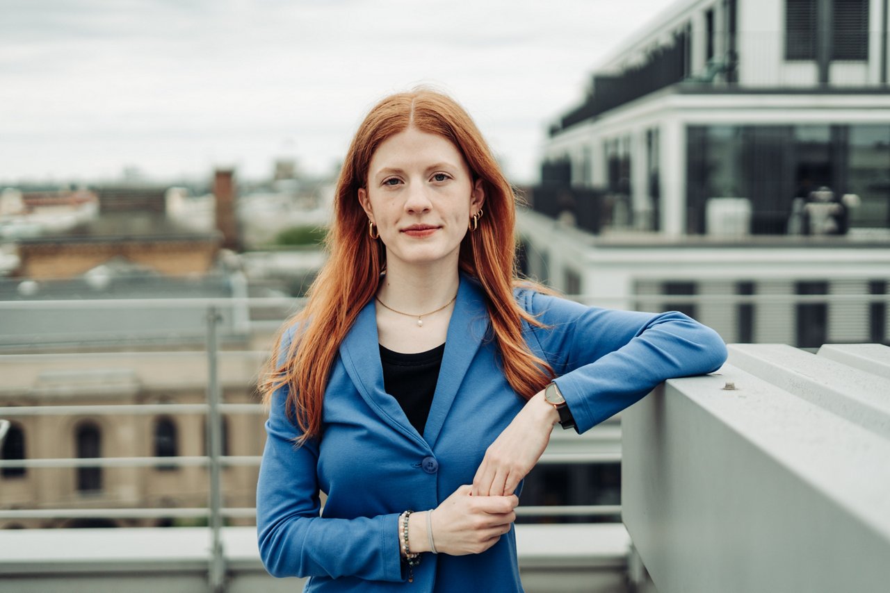 Trainee im Bereich Marketing, Kommunikation und Technologien auf einer Terrasse mit Arm auf einer Mauer