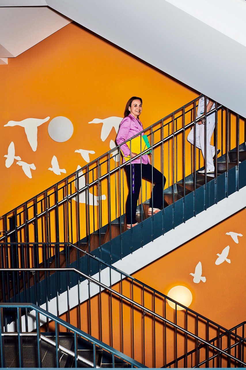 Assistentin der KGF geht die Treppen hoch mit Unterlagen unter Arm