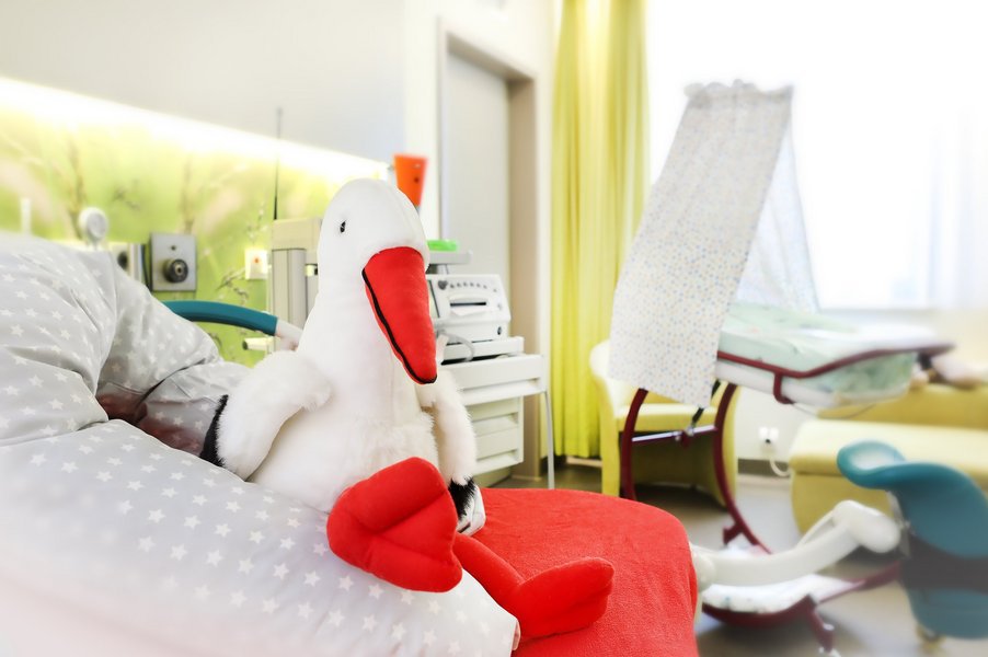 Ein großer Plüsch-Storch auf dem Geburtsbett im Kreißsaal