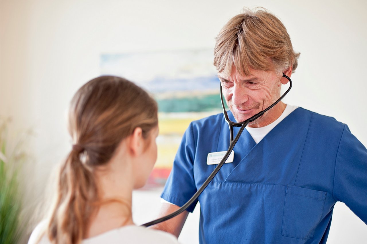 Chefarzt Dr. Streuter hört Lunge von Patientin mit Stethoskop ab 