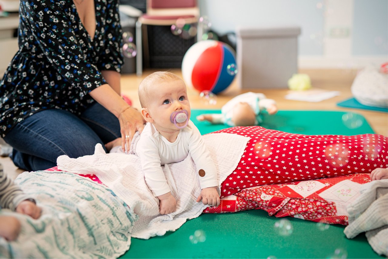 Kursleiterin mit Vater, der ein Baby in der Trage vor sich hat