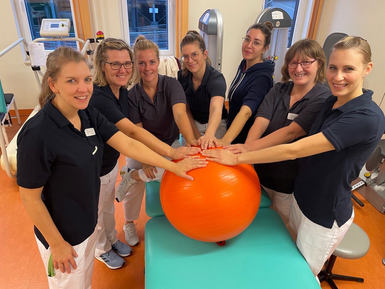 Mitarbeitende berühren orangen Medizinball