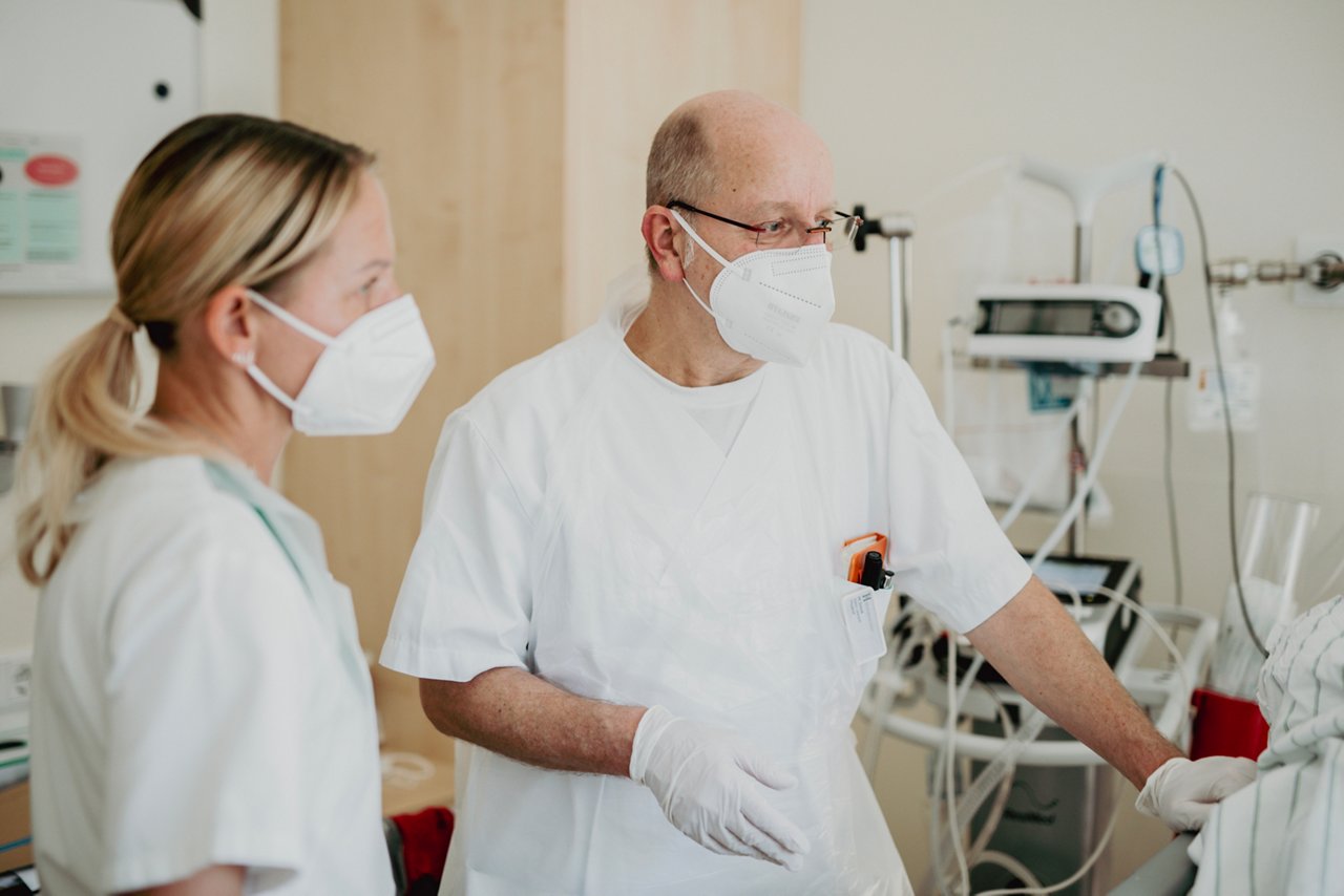 Mitarbeitende am Krankenhausbett im Gespräch mit Patient