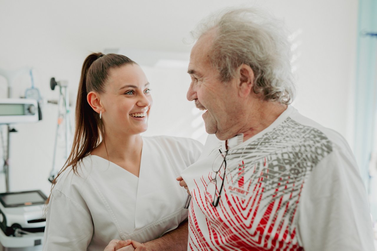 Pflegekraft hilft einem Patienten beim Gehen