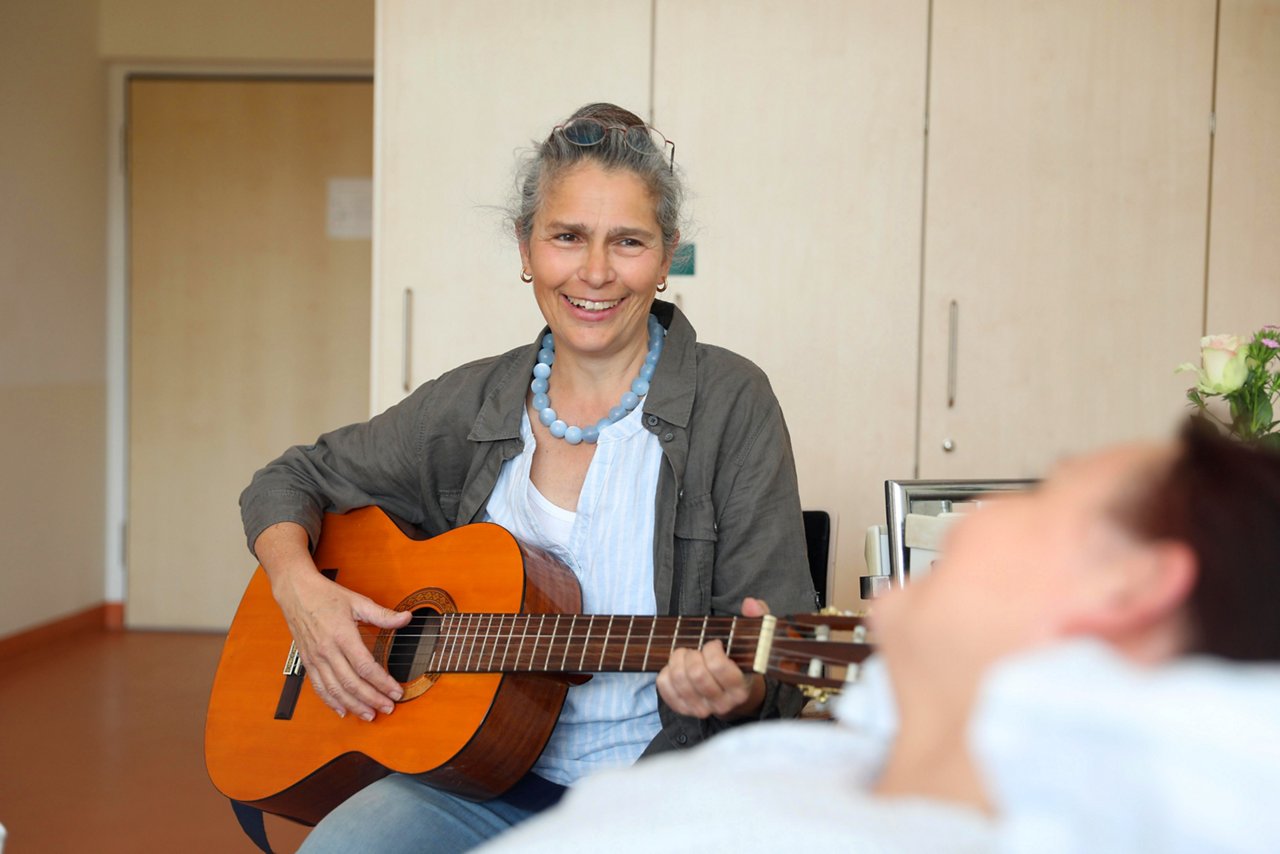 Eine Musiktherapeutin singt mit einer Patientin auf der Palliativstation