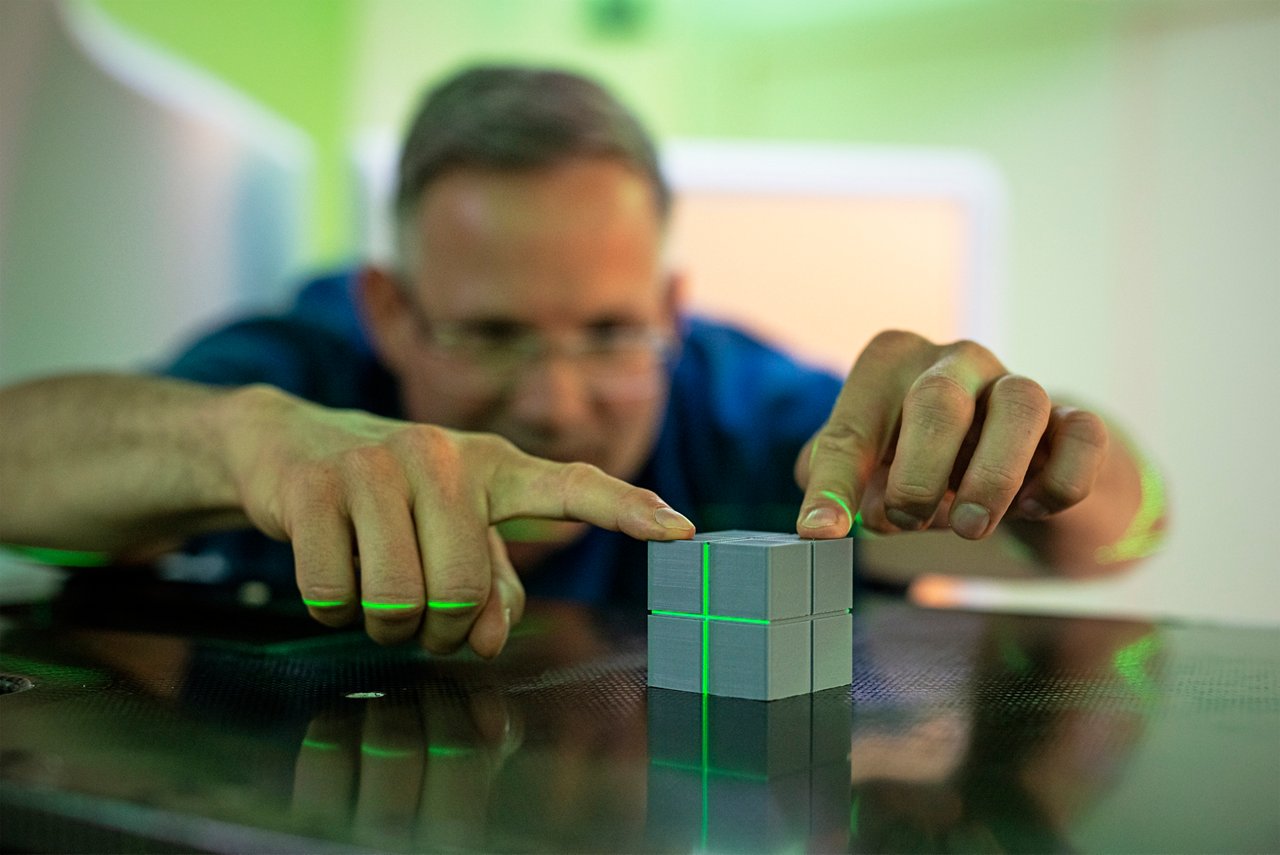 Laserstrahlen des Linearbeschleuniger zeigen auf einem Würfel in den Händen von Dr. Daum-Marzian, wie präzise die Bestrahlung erfolgt.