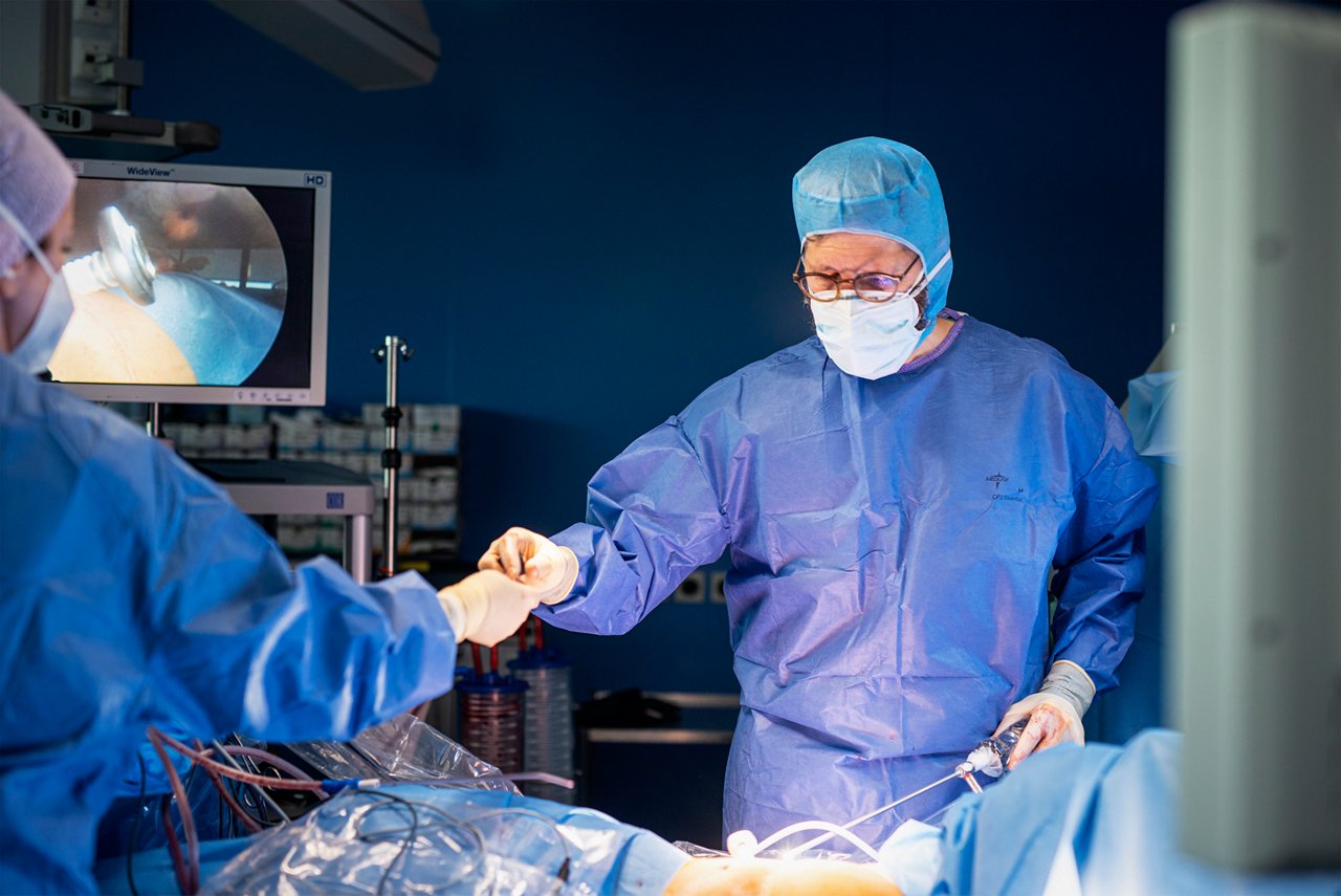Thoraxchirurg am OP-Tisch mit OP-Haube und Mundschutz während einer Lungenoperation