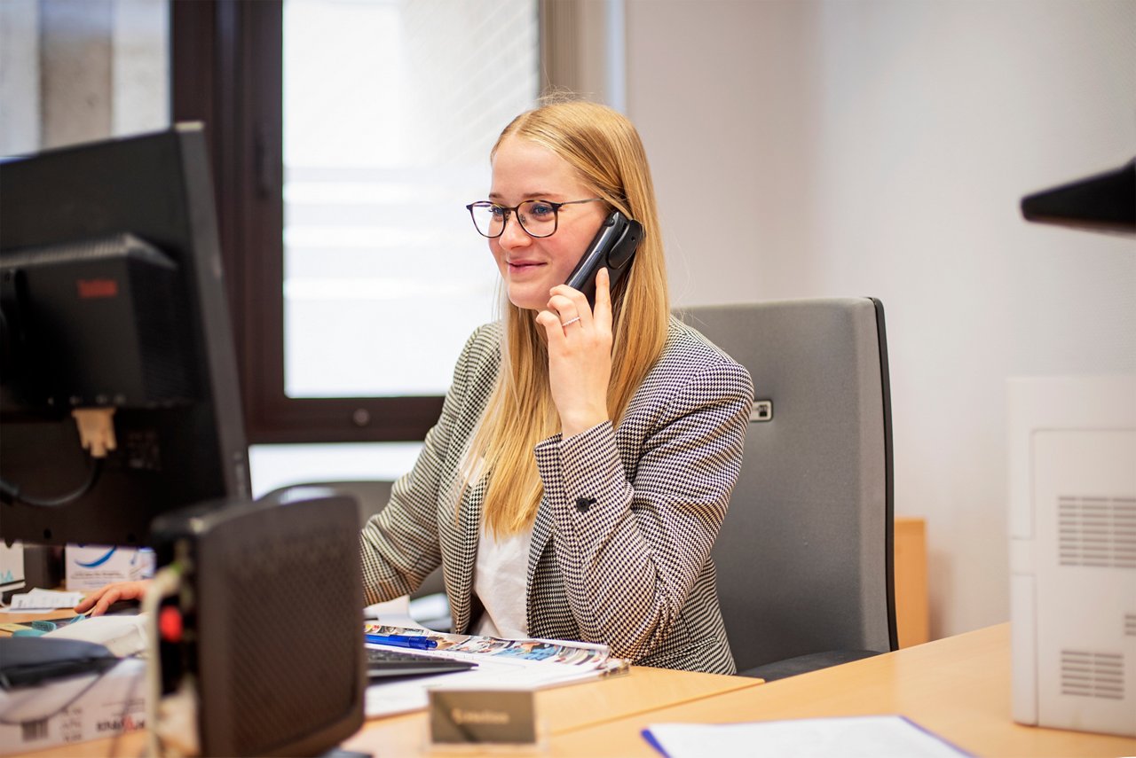 Mitarbeiterin am Telefon vor dem Computer