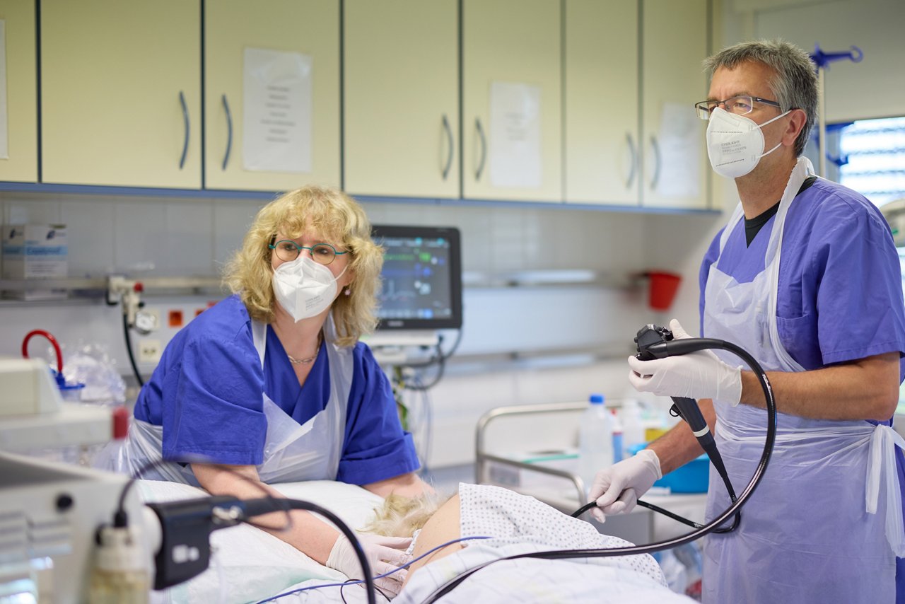 Pflegekraft zieht sich Handschuhe am Krankenbett über