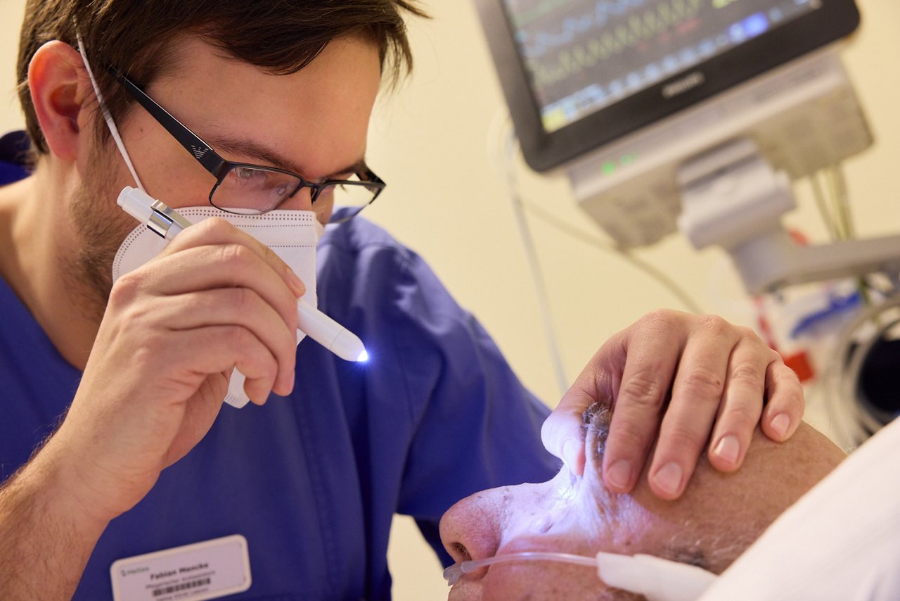Arztassistent führt Pupillendiagnostik bei einem Patienten durch.