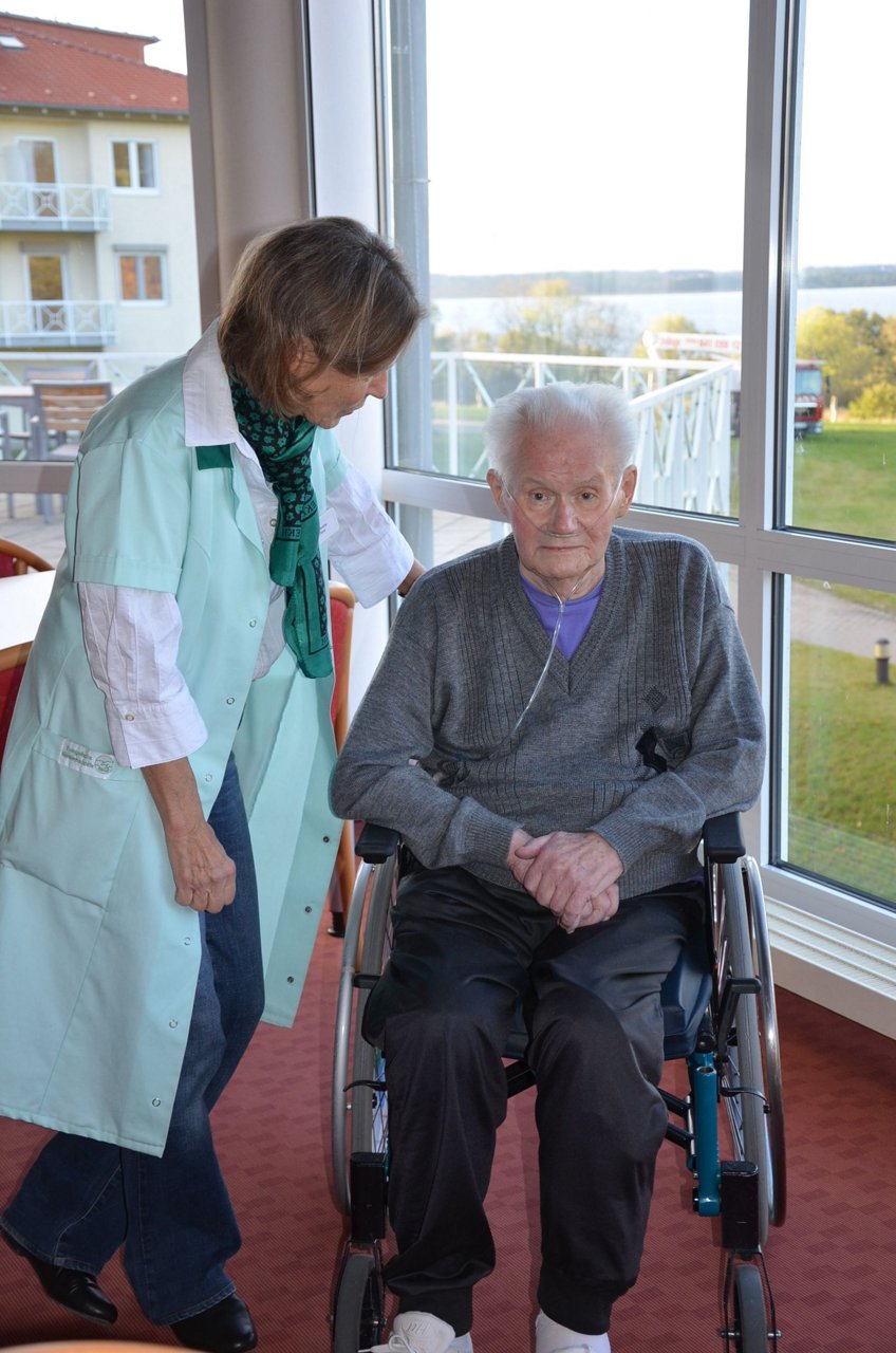 Ehrenamtliche Patientenbetreuerin im Gespräch mit einem Patienten im Rollstuhl