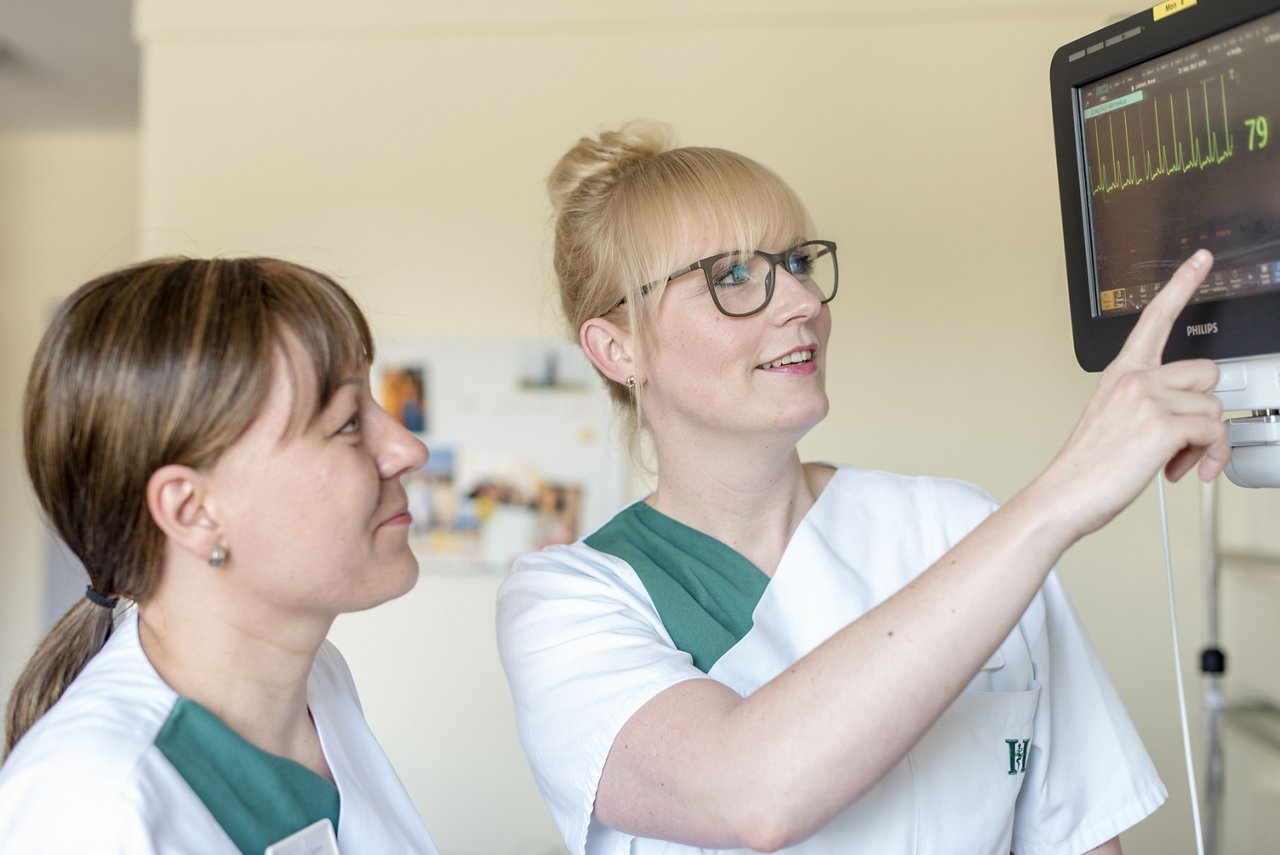 Krankenpflegerinnen überprüfen die Vitalzeichen eines Patienten am Monitor