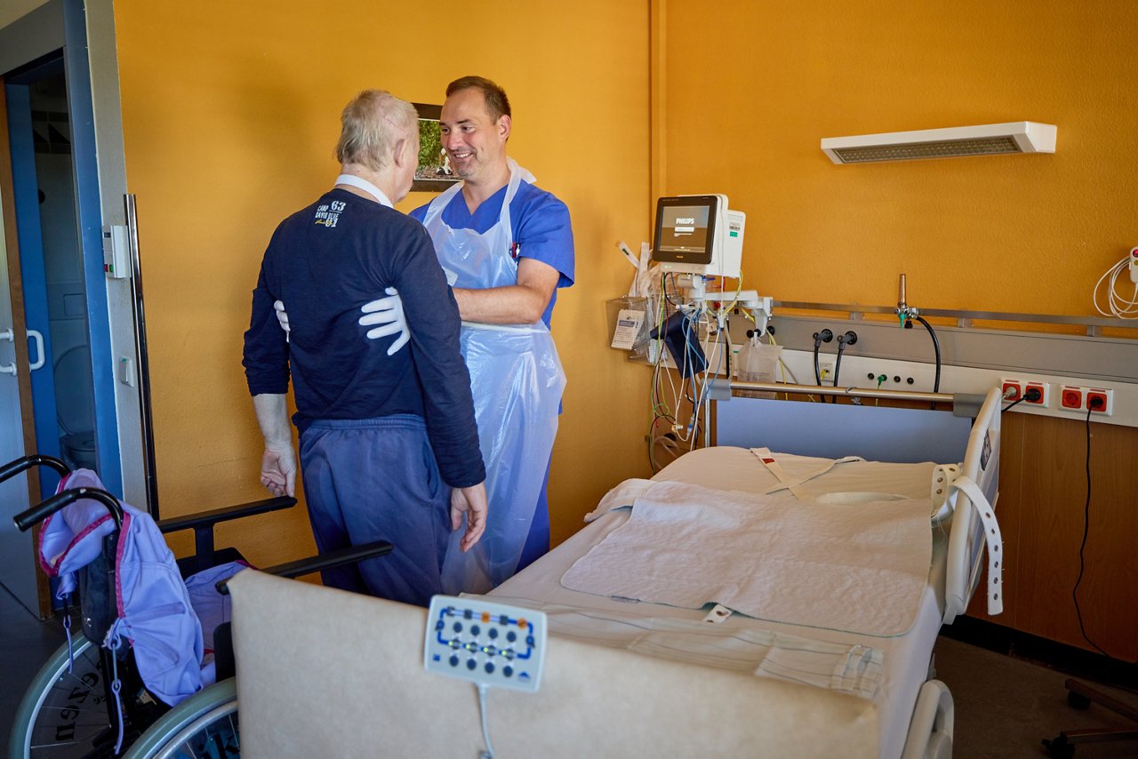 Pflegefachmann unterstützt Patienten beim Stehen