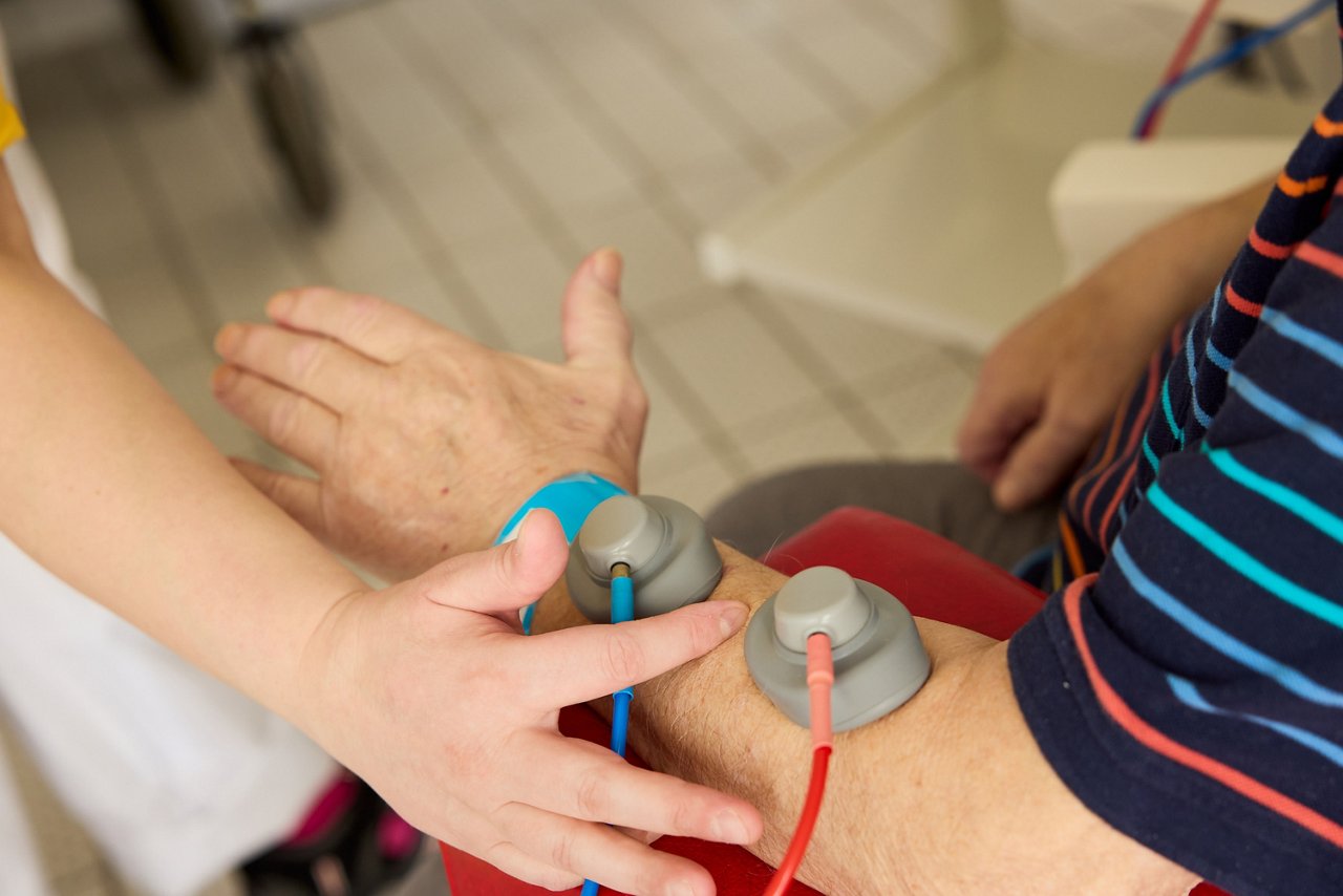 Therapeutin legt Elektroden auf den Arm eines Patienten