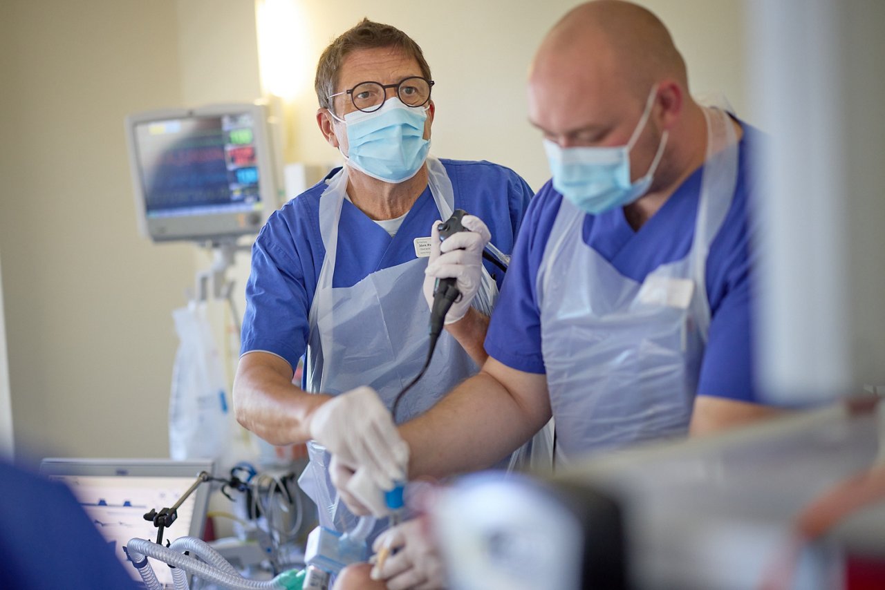 Arzt und Intensivpfleger untersuchen Patienten mit einem Bronchoskop