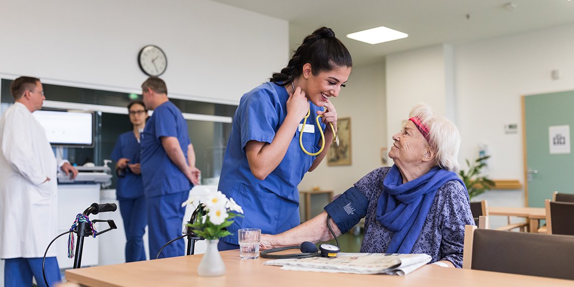 Geriatrie Pflegerin spricht mit Oma am Tisch