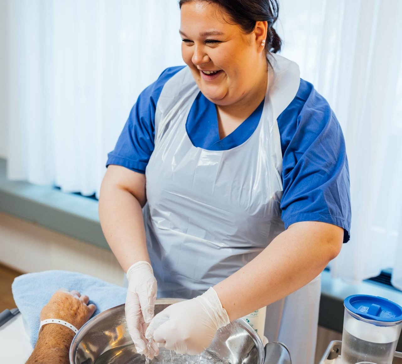 Eine KPH Auszubildende hilft einem Patienten bei der Körperhygiene.