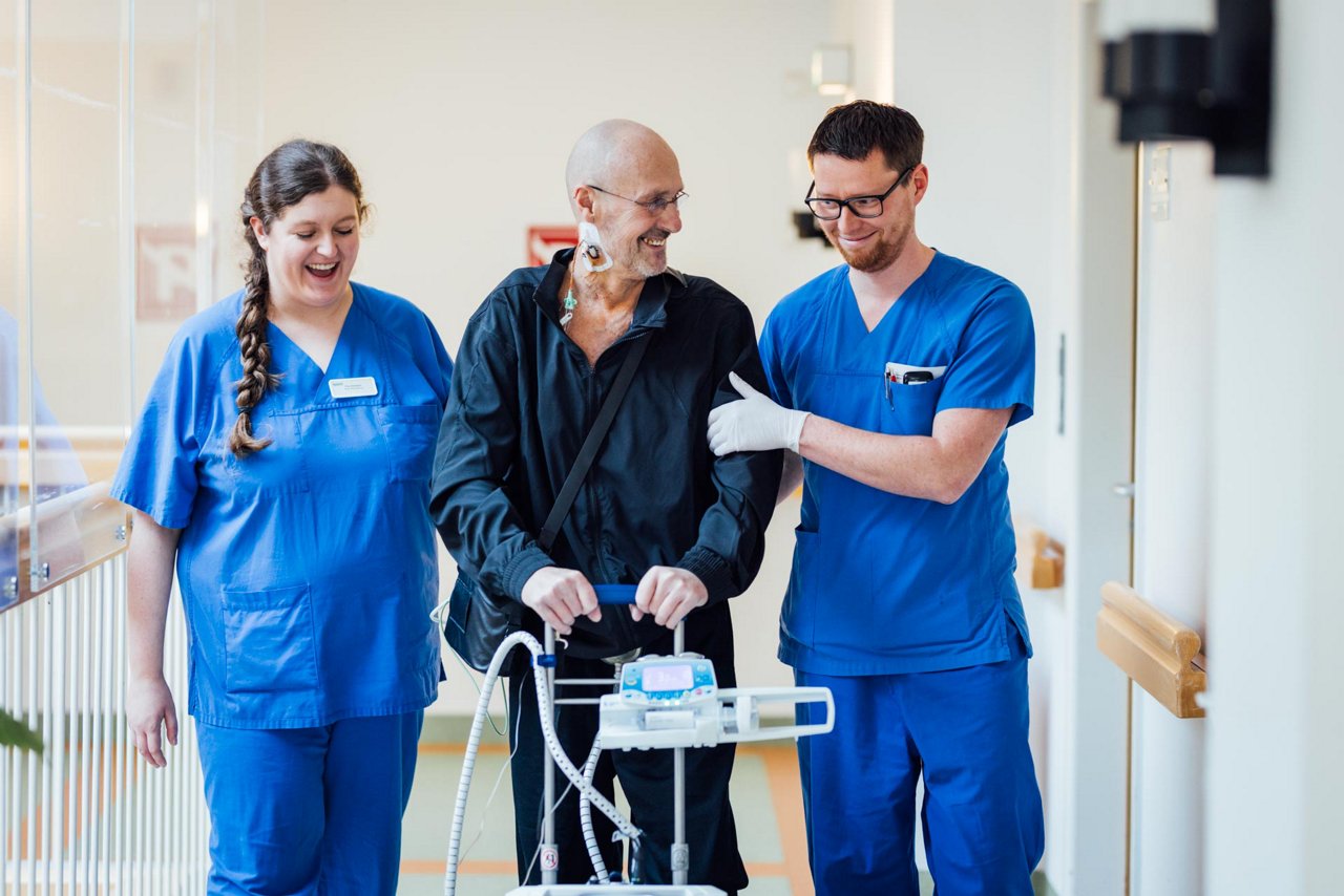 Pfleger gießt Opa etwas zu trinken ein