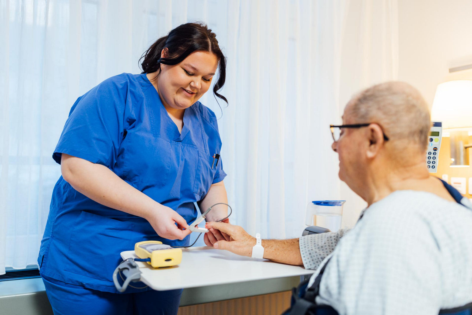 Krankenpflegehelfer-Auszubildende Pia misst den Puls eines Patienten