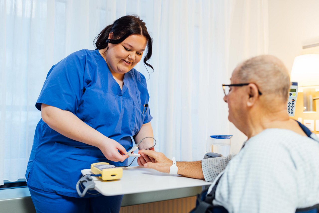 Krankenpflegehelfer-Auszubildende Pia misst den Puls eines Patienten