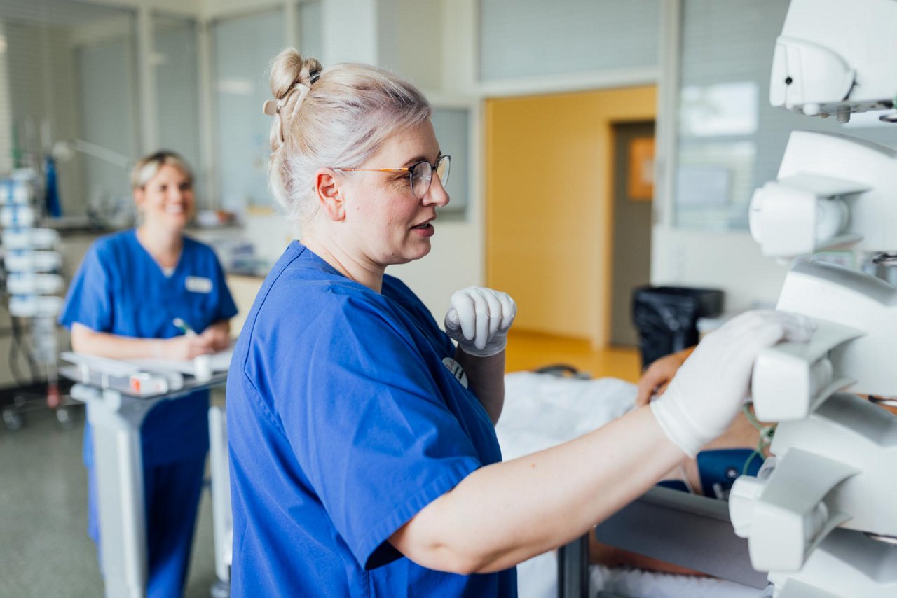 Pfleger gießt Opa etwas zu trinken ein