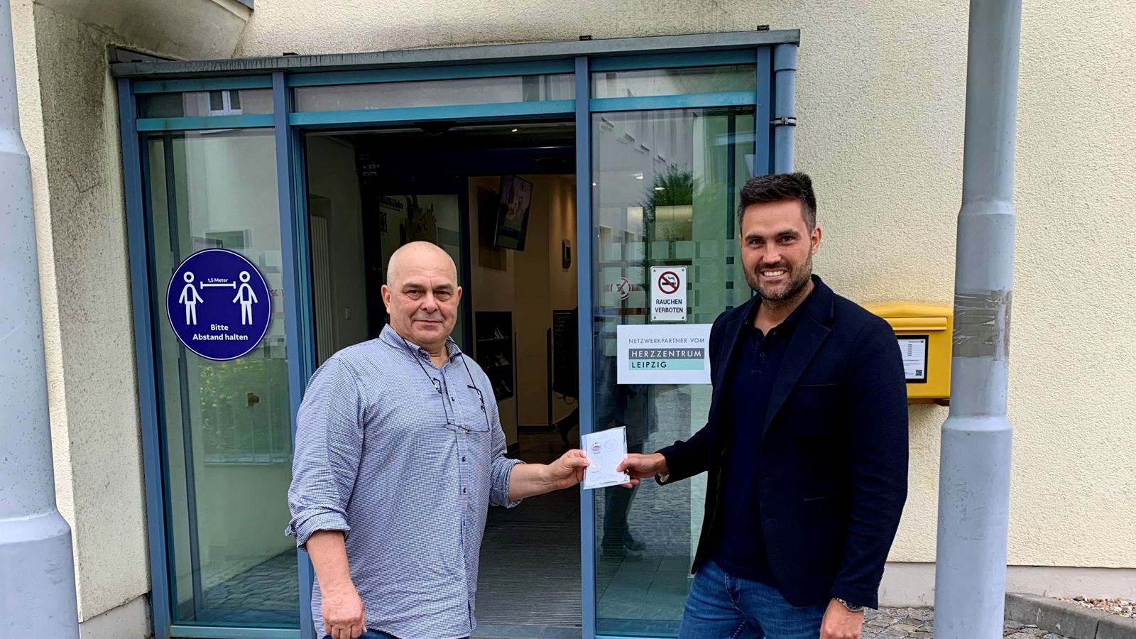 Uwe Reichel, Vorsitzender des Leisniger Geschichts- und Heimatvereins, überreicht die Festmünze feierlich an Julian Zimmer, Geschäftsführer der Helios Klinik Leisnig 