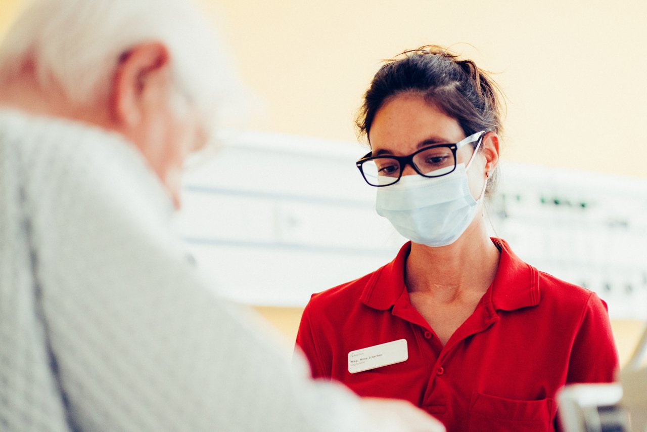 Logopädin und Patient blicken scheinbar auf den Tisch, der nicht mit im Bild ist