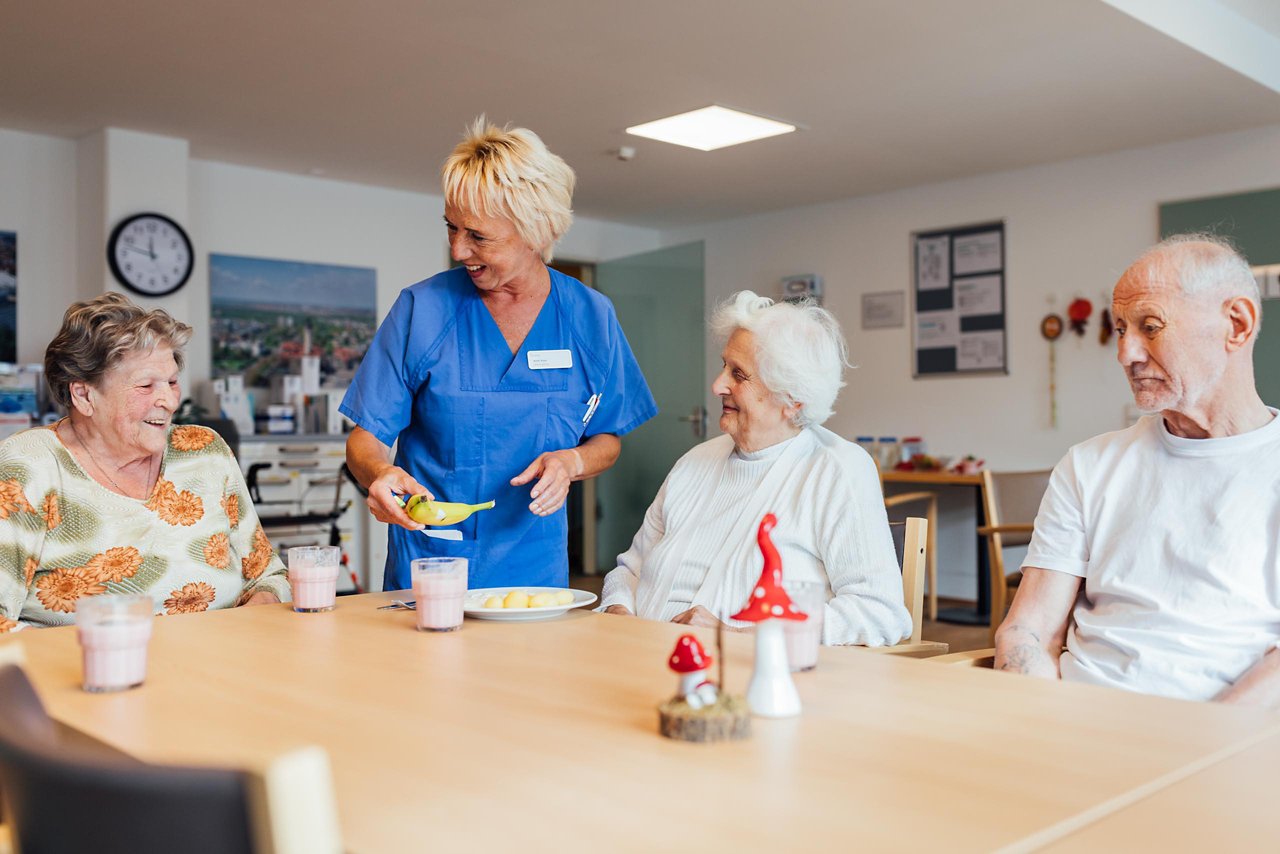 Patient:innen und Pflegekraft am Tisch