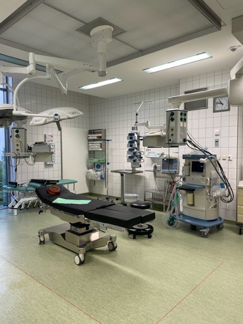 OP mit Patientenliege in der Mitte des Raums und vielen OP Geräten