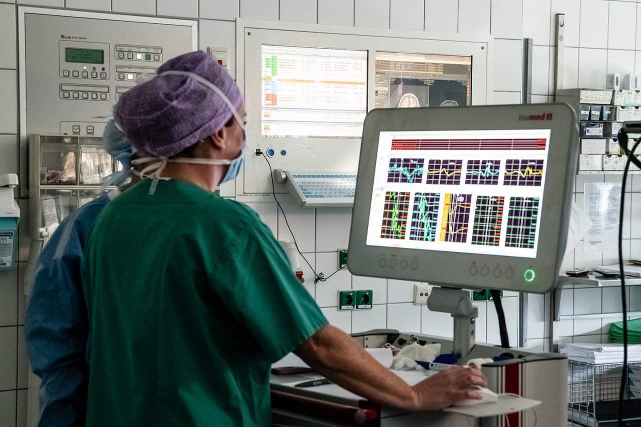Großer Bildschirm mit verschiedenen Werten wird von Ärztin überwacht