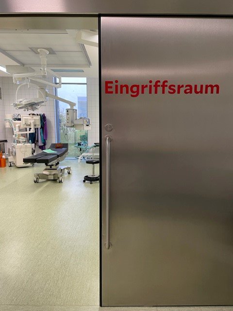 Notfallmedizinischer Raum mit Tür auf der Eingriffsraum geschrieben steht