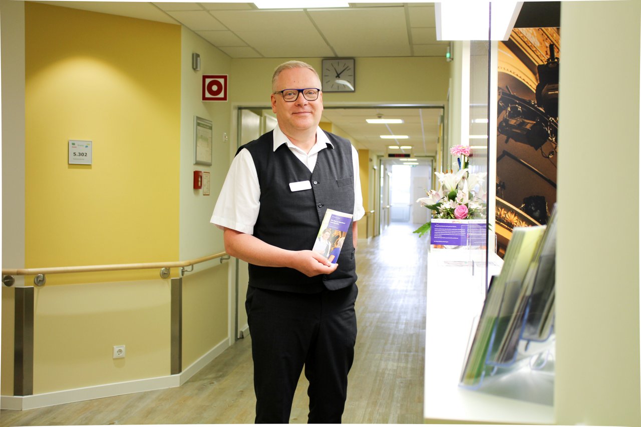 Manager der Wahlleistungsstation präsentiert im Gang den neuen Flyer.