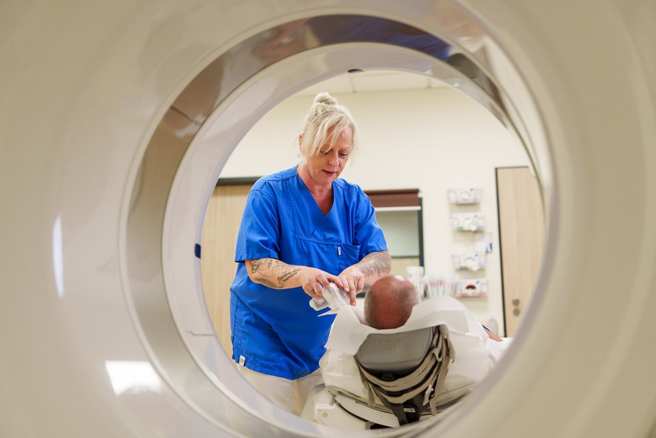 Assistentin bereitet Patienten für seine Untersuchung im Computertomograph vor