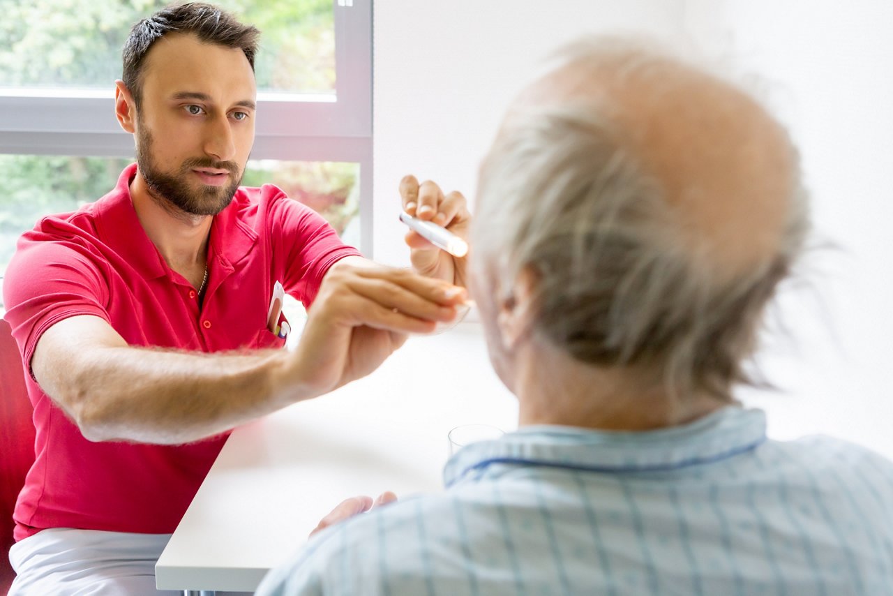 Logopäde untersucht älteren Patienten