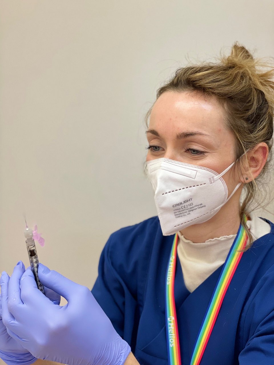 Ärztin zieht Injektion auf mit Handschuhen und Maske