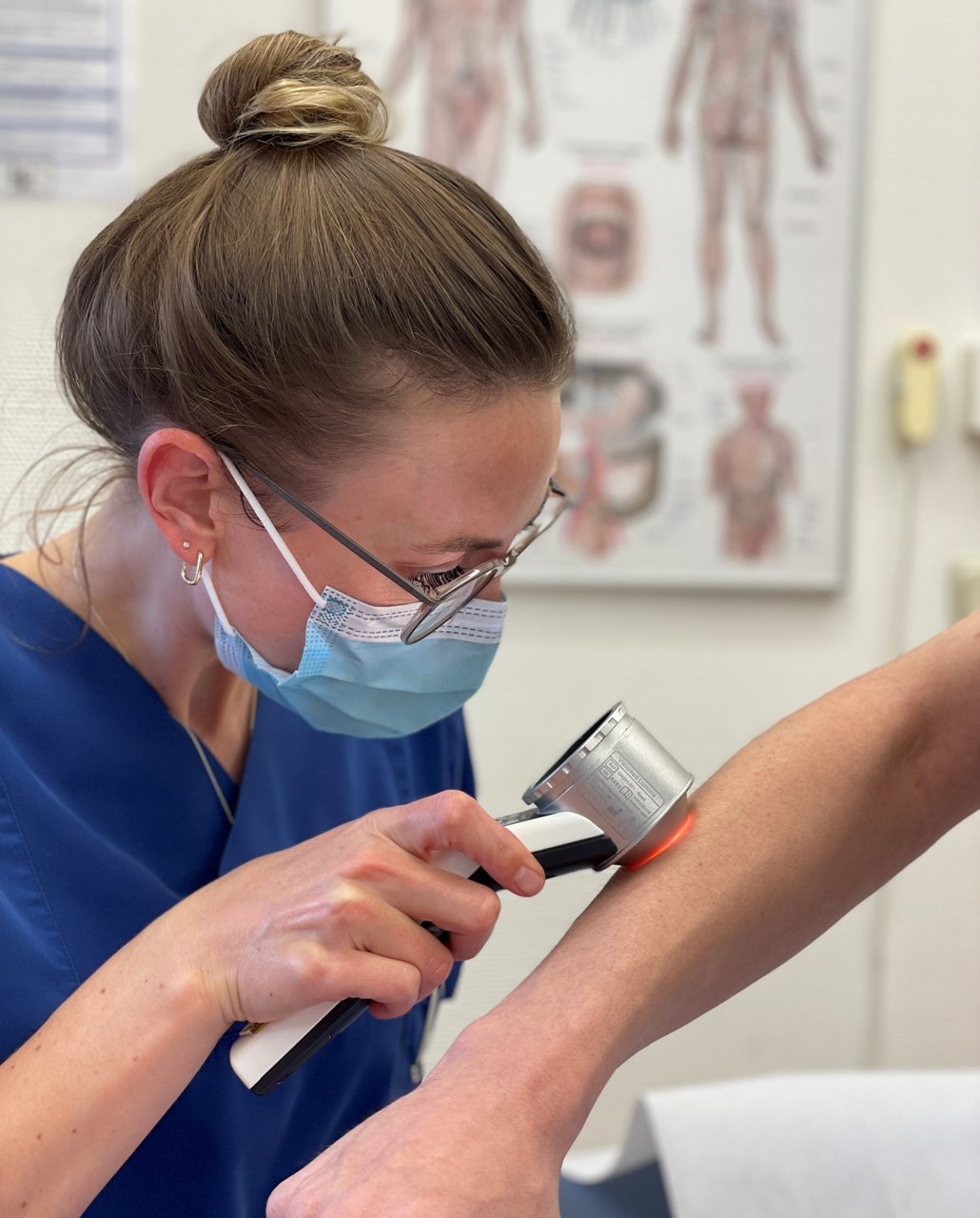 Ärztin untersucht Arm mit Auflicht zu Hautkrebs