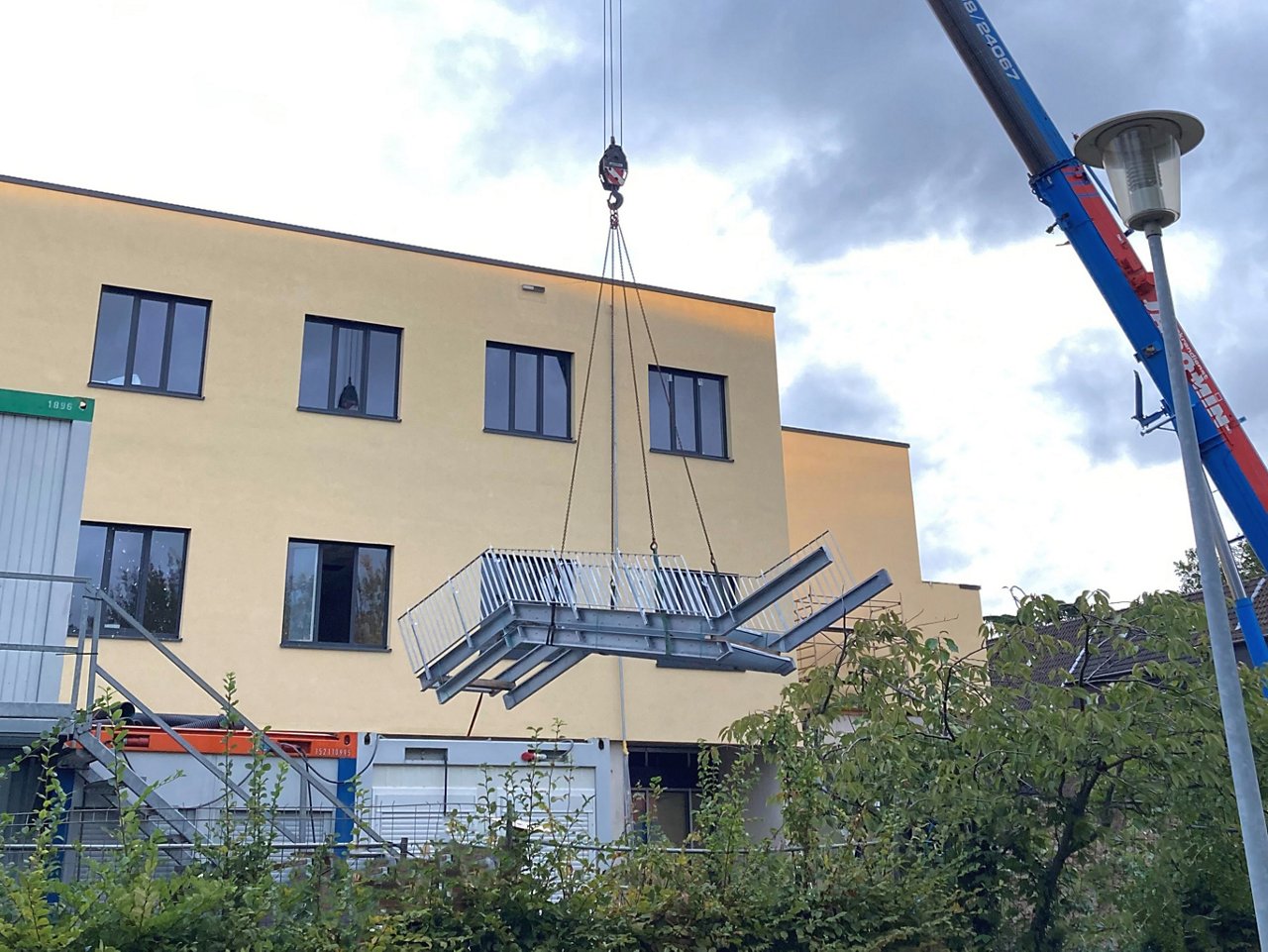 Kran transportiert Außentreppenelement zur Baustelle