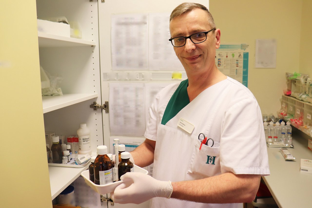 Pflege sucht Medikament aus Medikamentenschrank im Stationszimmer